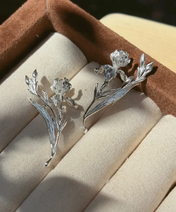 Handmade iris earrings in the Bud and Leaf style arranged as a pair in a brown jewelry box