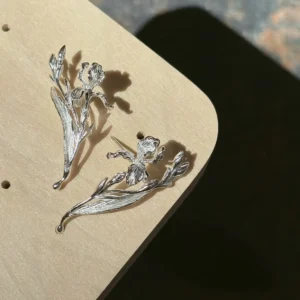 Bud and leaf sterling silver iris earrings photographed as a pair in soft shadow