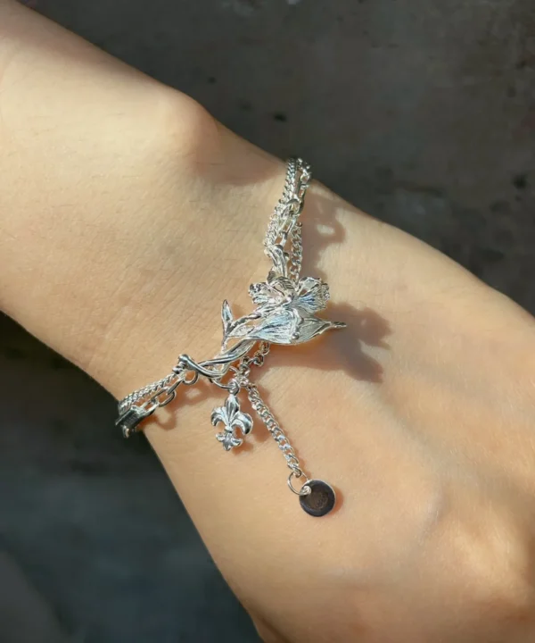 Personalized iris bracelet worn on the wrist with layered chains and moving charms