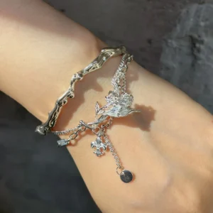 Iris bracelet worn across the wrist with a sculpted silver flower and dangling emblems