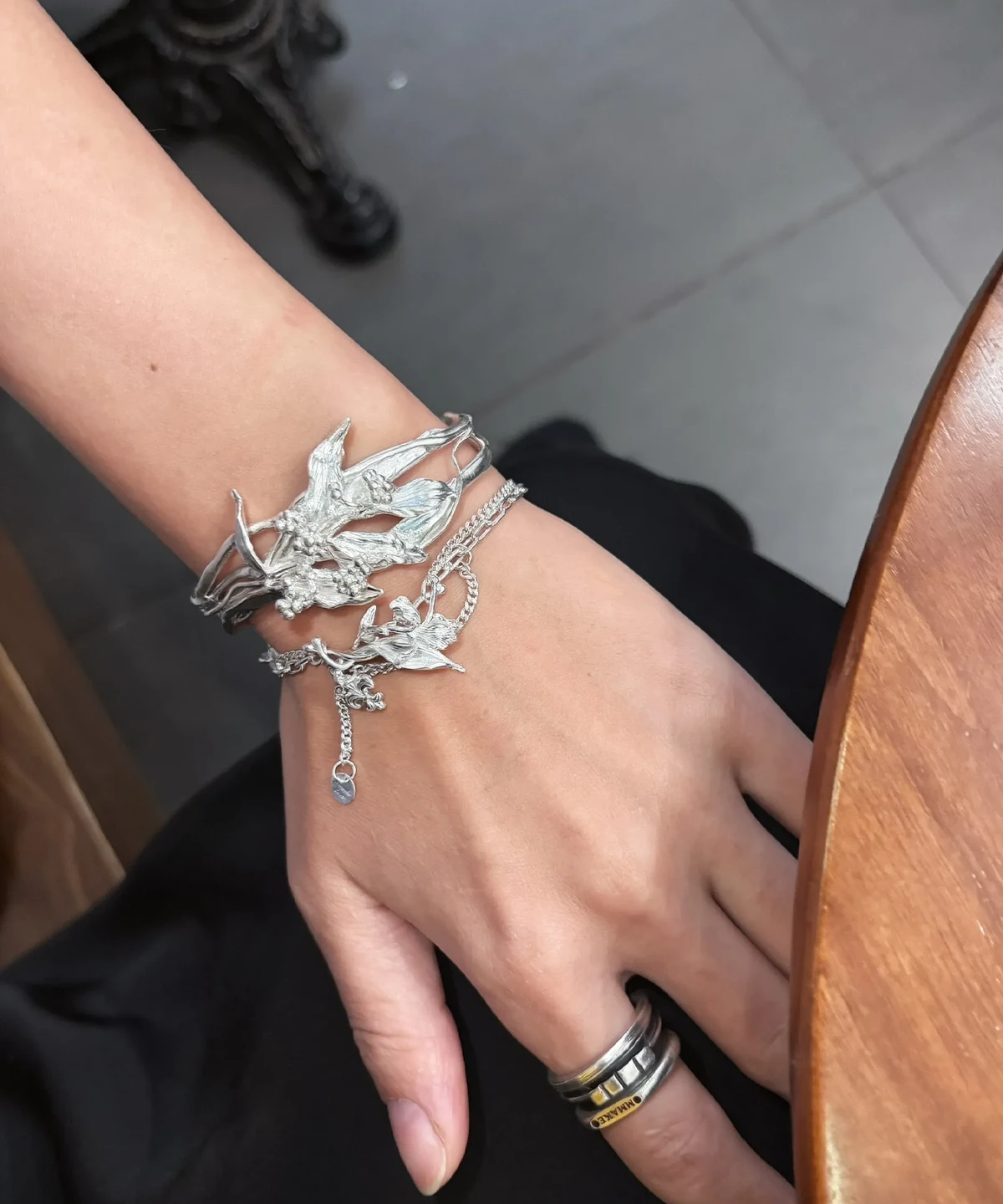 Handmade silver bracelet with iris flower and personalized charms worn beside a dark outfit