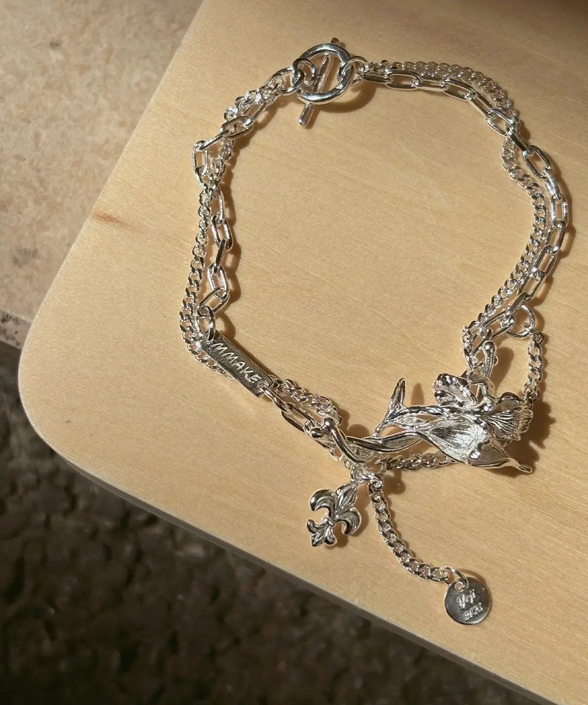 Personalized silver iris bracelet with engravable plate and round medallion shown flat