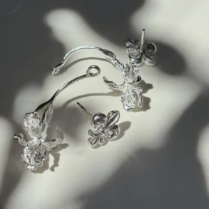 Handmade silver ear jacket earrings photographed in leaf-filtered sunlight, four-piece construction visible