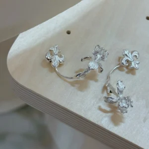 Silver ear jacket stud earrings arranged on a white ridged surface with both back pieces detached