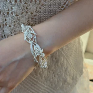 Silver iris flower cuff bracelet worn on the wrist with openwork stems, buds, and blossoms