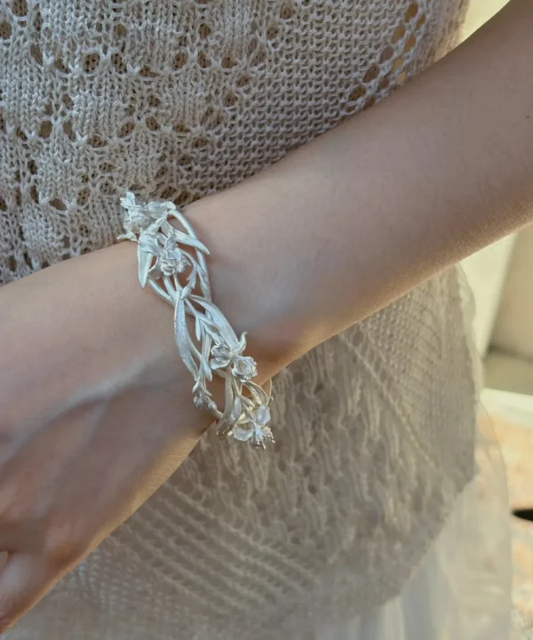 Silver iris flower cuff bracelet worn on the wrist with openwork stems, buds, and blossoms