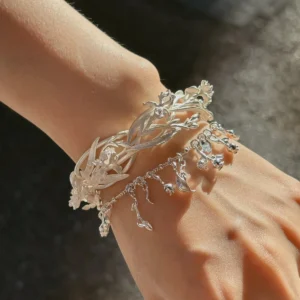 Floral cuff bracelet worn in sunlight with sculpted iris flowers and layered silver leaves
