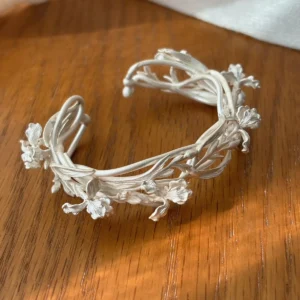 Silver flower cuff bracelet viewed from above with open ends and layered iris branches