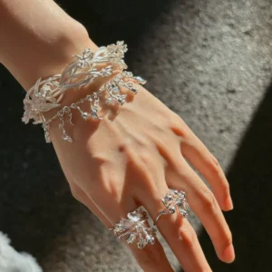 Wide floral cuff bracelet in silver worn across the wrist with intertwined botanical detail