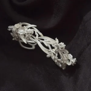 Silver iris cuff bracelet close up on black fabric with detailed petals, buds, and long leaves
