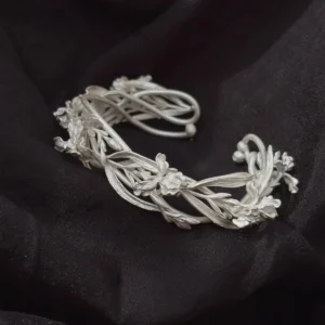 Flower cuff bracelet displayed open on black fabric with its full silver botanical band visible