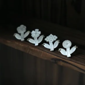 Botanical stud earrings in four flower shapes, lined up in silver
