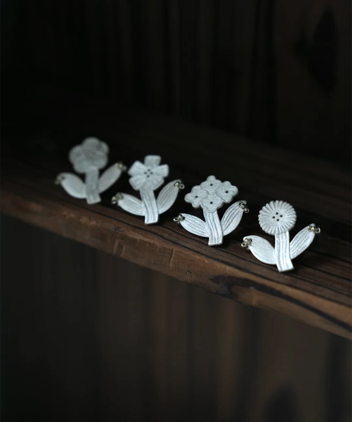 Botanical stud earrings in four flower shapes, lined up in silver