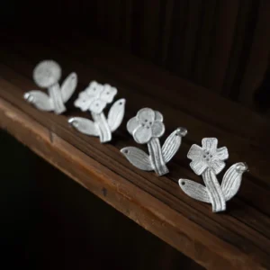 earring-designs-brushed-silver.webpFour flower stud earring designs in brushed sterling silver on dark wood