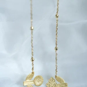 Detail of the gold flower necklace — beaded chains ending in a round bloom and a four-bloom cluster with leaves