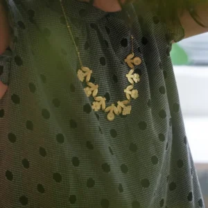 Gold flower necklace worn with a dotted green blouse, garland resting below the collar