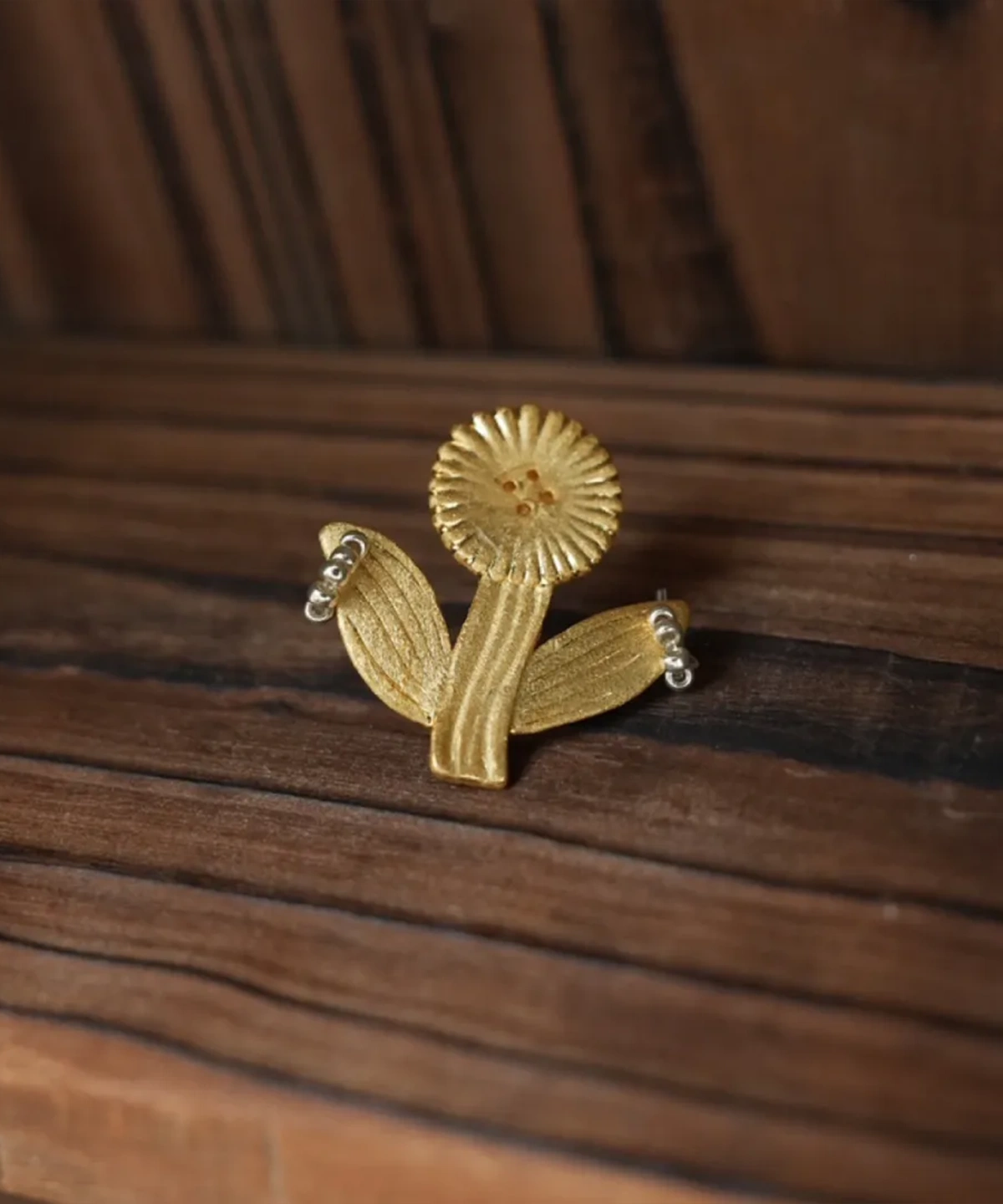 Round fringe-petal gold flower stud earring on warm wood (Style 1)