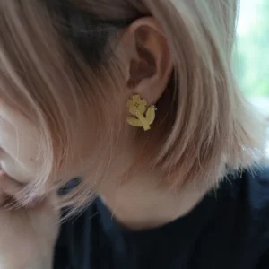 Gold flower stud earring worn on the ear, whole flower with stem and leaf