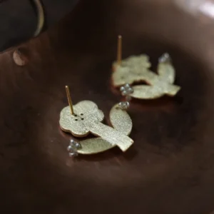 Backs of two gold flower stud earrings resting in a copper dish
