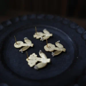 Backs of four gold flower stud earrings on a black ceramic plate, posts showing