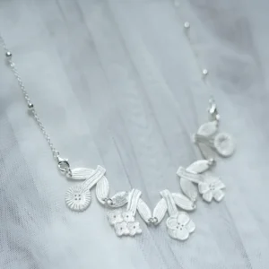 Morning Dew flower necklace in silver on sheer white fabric, garland of five flowers between leaf pairs