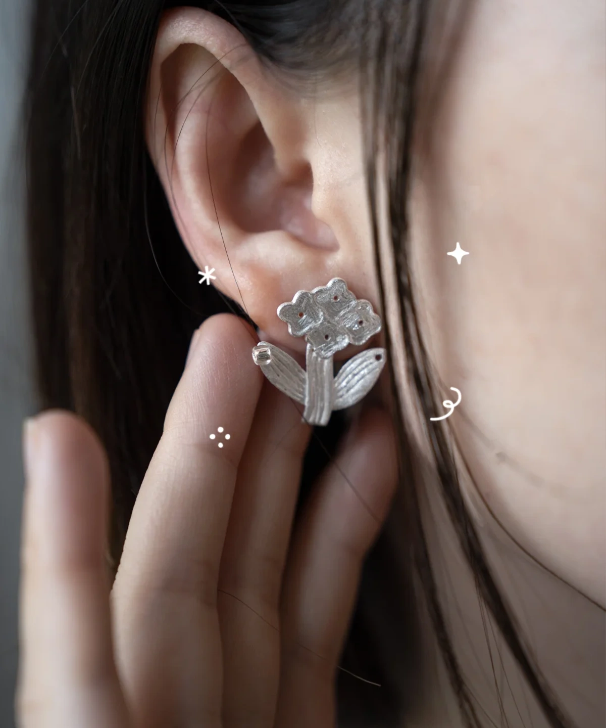 Silver flower stud earrings. worn on the ear, small bloom cluster with stem and leaves