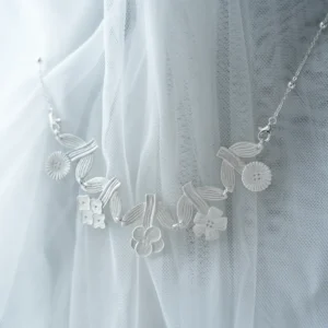 Silver flower necklace resting on white tulle, brushed blooms with a fine beaded chain
