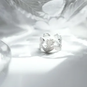 Silver flower ring standing on a white surface in rippled light, open garland band