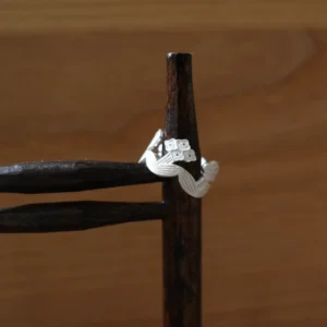Silver flower ring resting on a dark iron stand, showing the open band