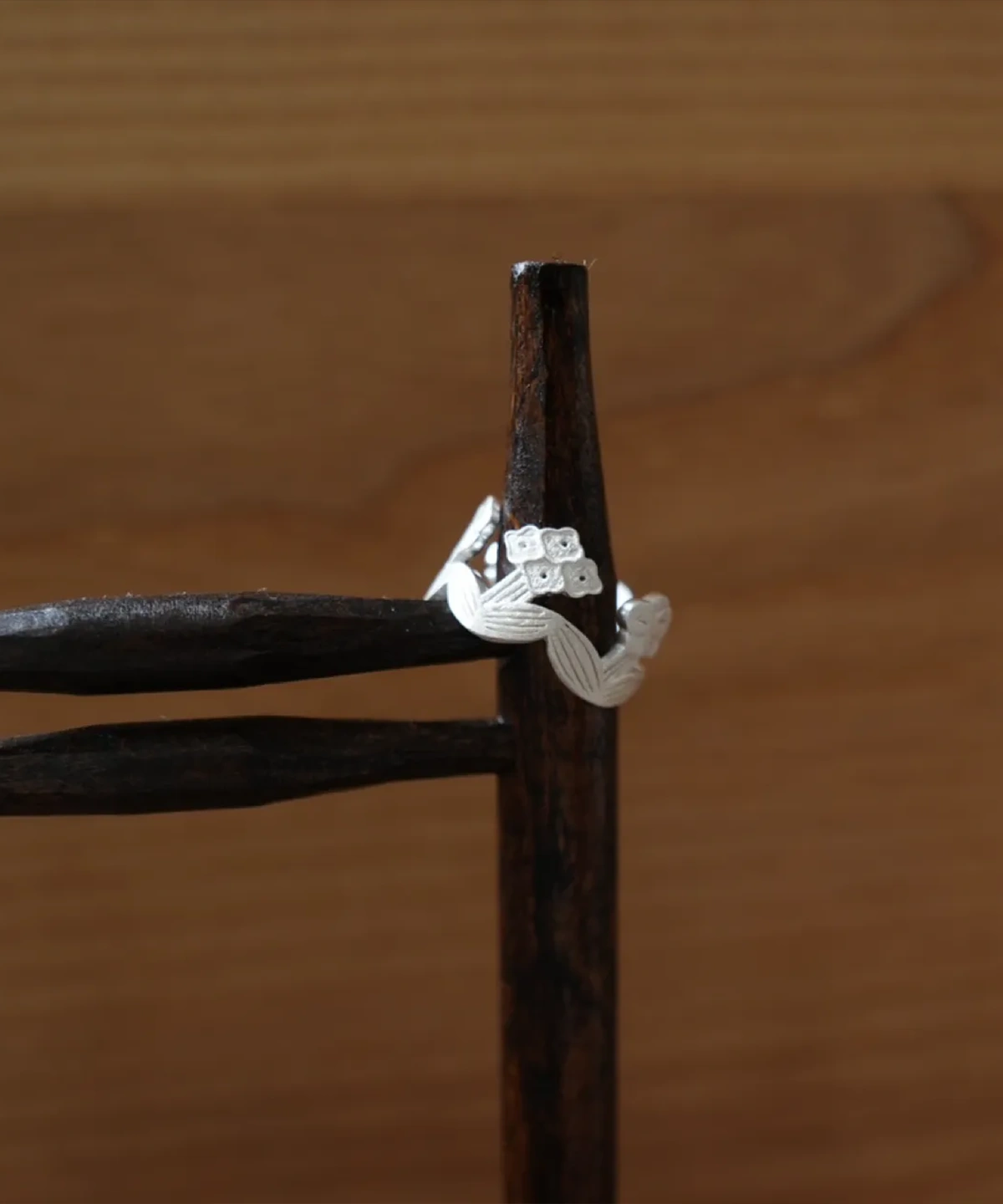 Silver flower ring resting on a dark iron stand, showing the open band