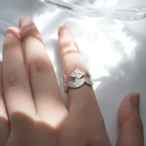 Silver flower ring worn on the finger in dappled sunlight, blooms and leaves circling the band