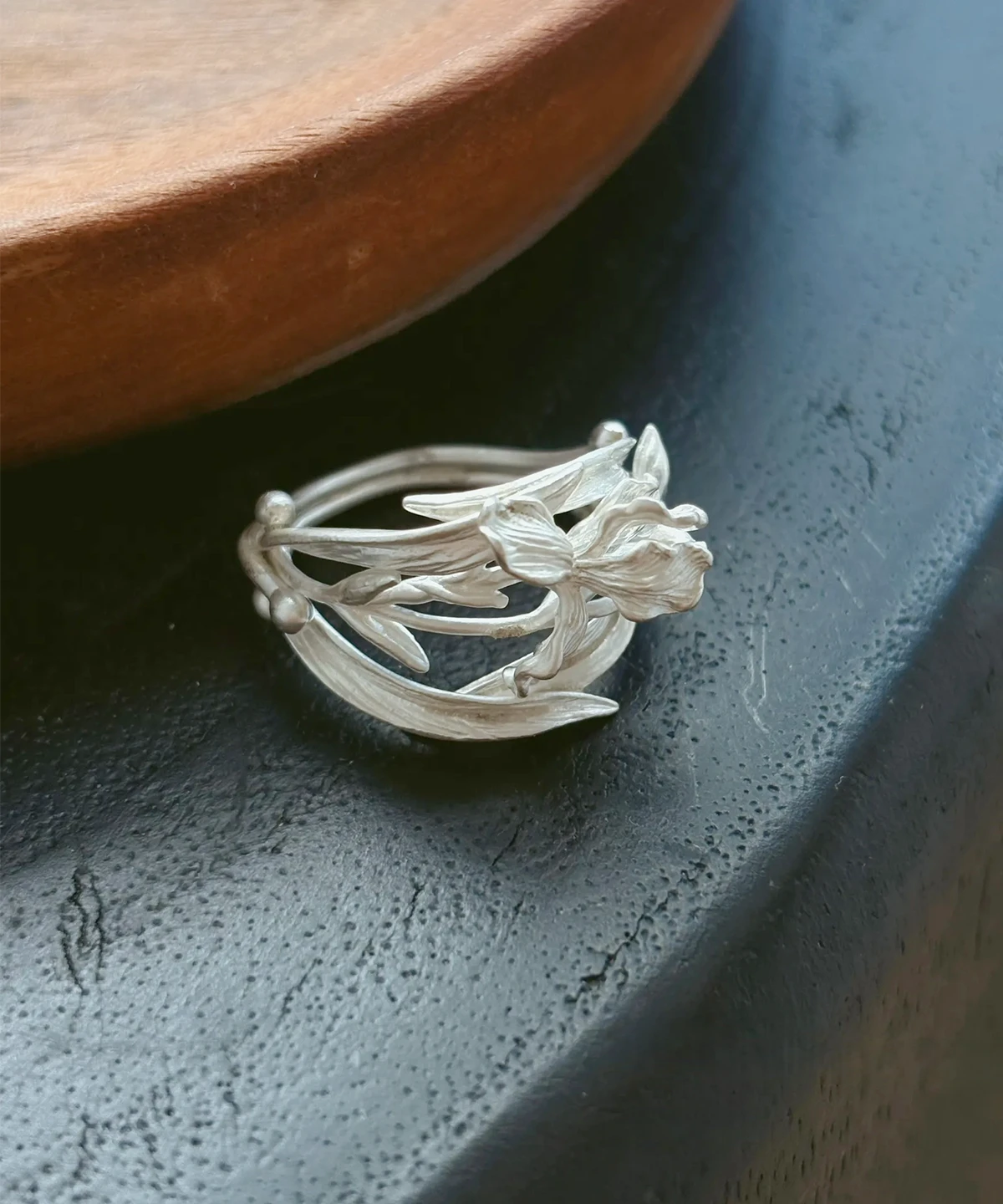 Handmade silver iris ring in S925 sterling silver resting on a dark vessel rim