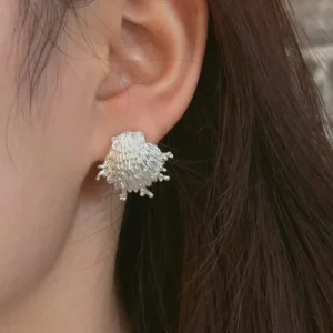 Frayed silver shell earrings worn on the ear, ribs breaking into fringed tips at the edge