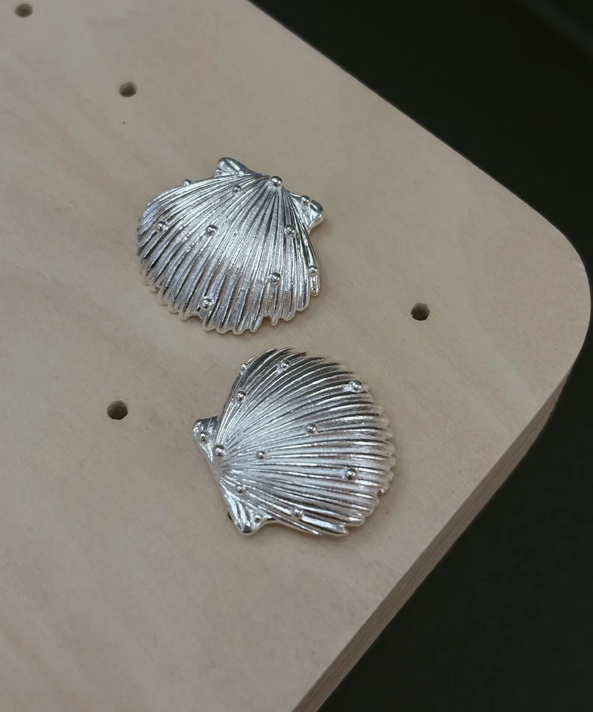 Ribbed scallop silver shell earrings in 990 pure silver, raised granules scattered across the fluting