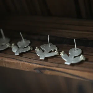 Row of small flower stud earrings standing on a wooden ledge