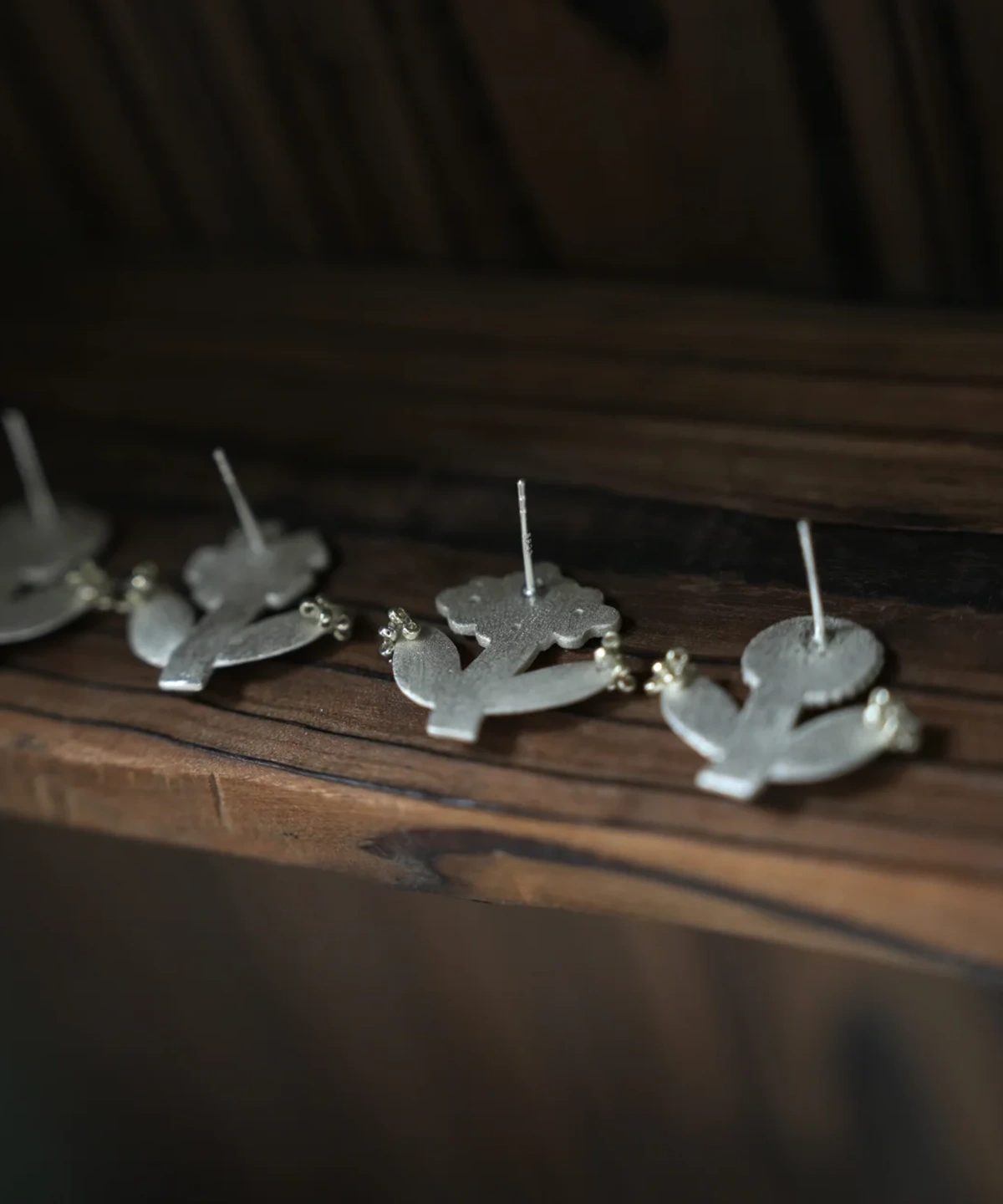 Row of small flower stud earrings standing on a wooden ledge