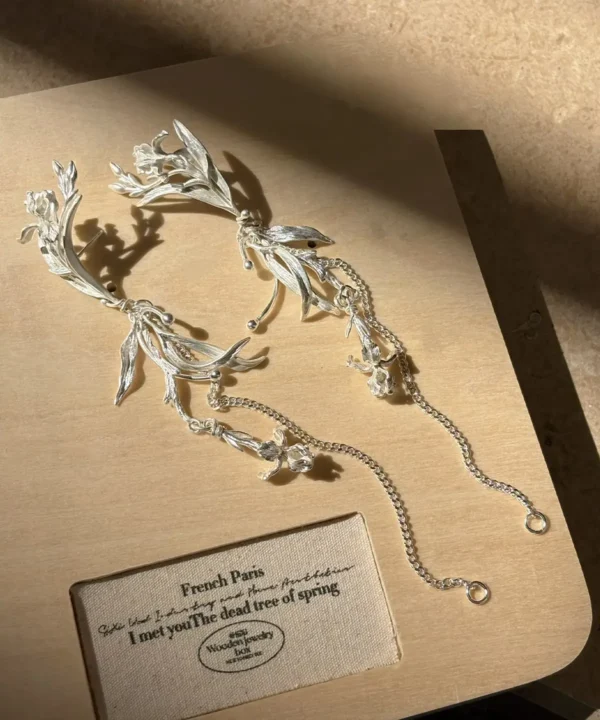 Sterling silver iris floral dangle earrings displayed as an asymmetric pair with long chains