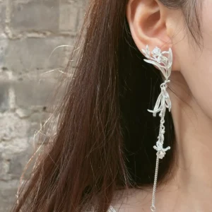 Long sterling silver iris dangle earring worn beside the face with a chain extending toward the shoulder