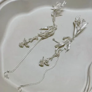 Sterling silver chain dangle earrings shown from above with posts, flower charms, and long chains visible