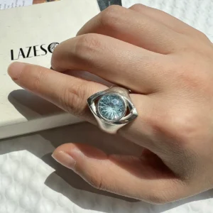 Silver gemstone ring with blue topaz worn on hand, featuring the unique Six Eyes Ring design