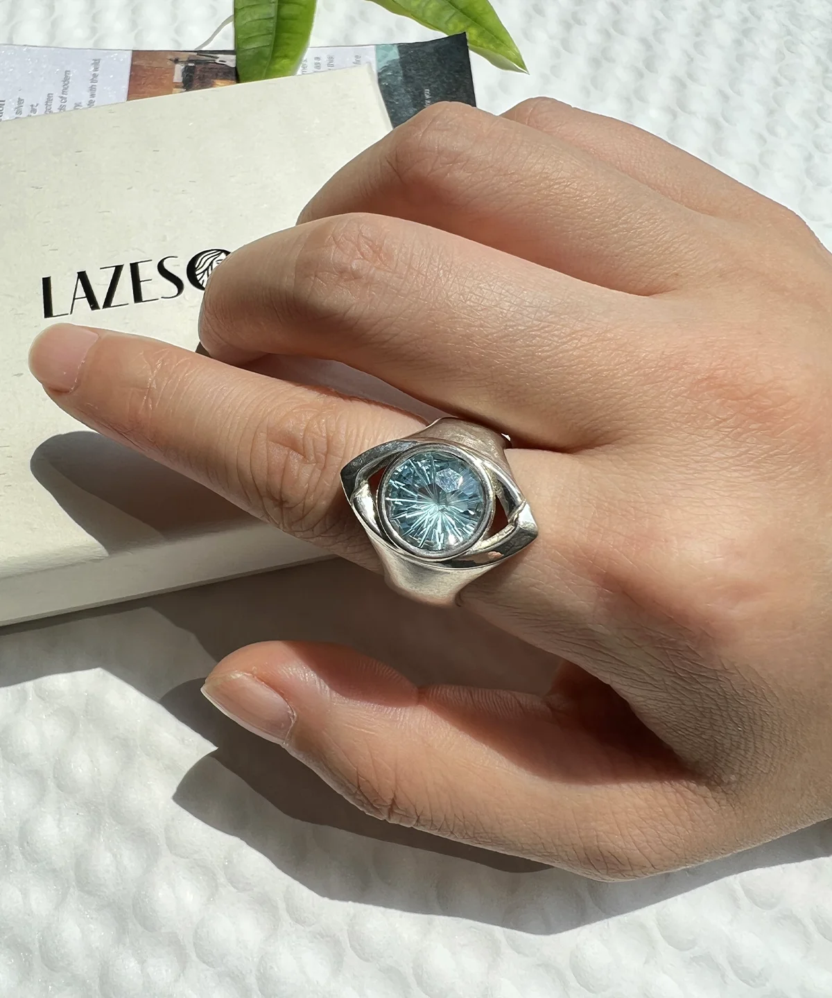 Silver gemstone ring with blue topaz worn on hand, featuring the unique Six Eyes Ring design