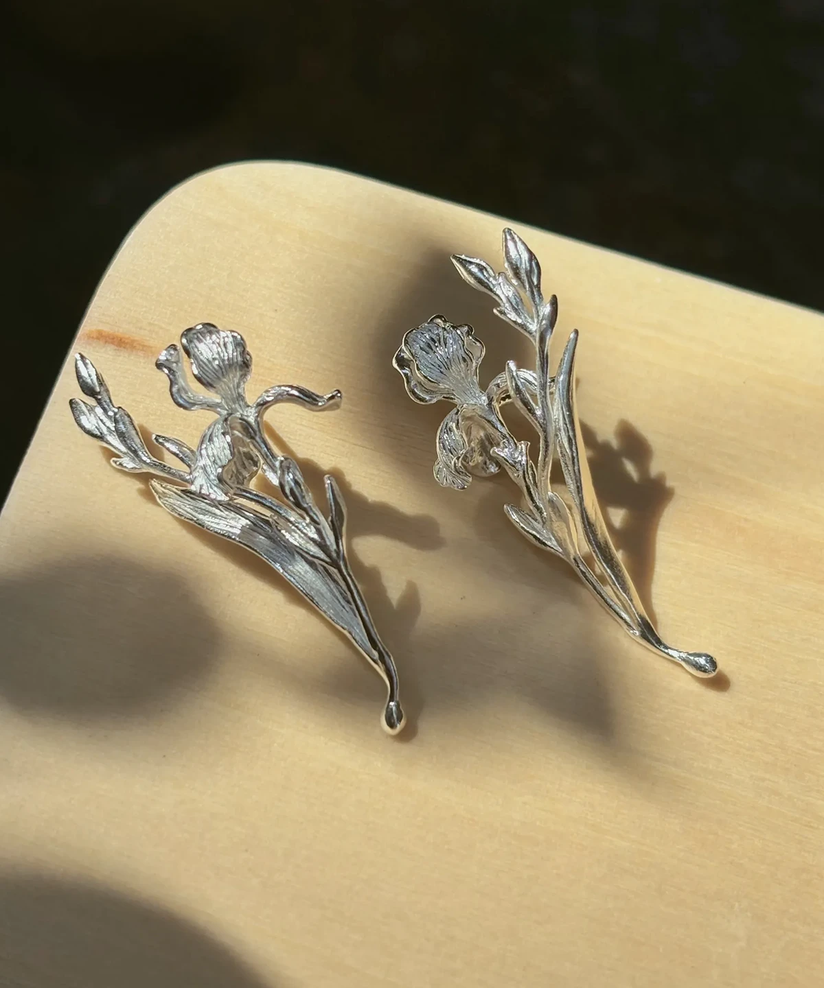 S925 silver iris earrings with blooms, buds and long leaves in warm side light