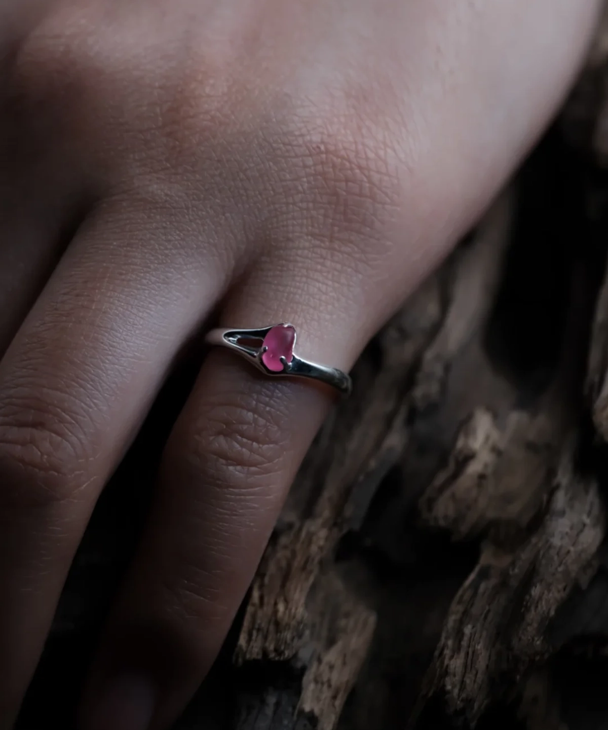 Delicate natural pink sapphire ring in S925 sterling silver worn beside textured wood