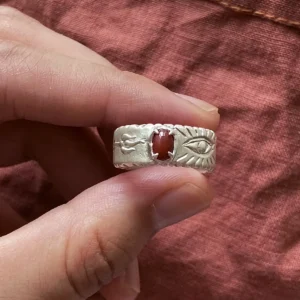 Handmade red agate ring in 999 fine silver held against rust-colored linen