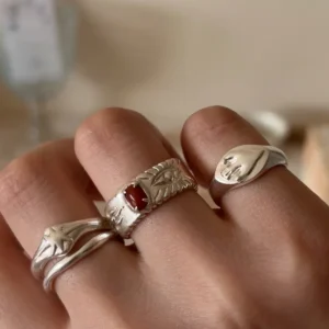 Red agate ring in 999 fine silver worn with other sculptural silver rings on a hand