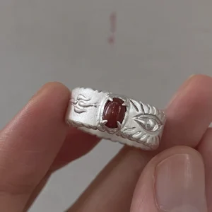 Red agate ring in 999 fine silver with natural Nanhong agate and an eye motif, held between fingers