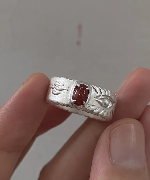 Red agate ring in 999 fine silver with natural Nanhong agate and an eye motif, held between fingers