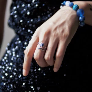 Silver lapis lazuli star ring worn on one hand against black sequins