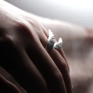 Sculptural profile of a twin-wing sterling silver ring on a dark background