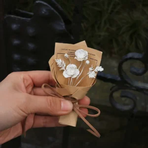 Handheld two-bloom 950 silver poppy bouquet in kraft paper against a dark garden bench